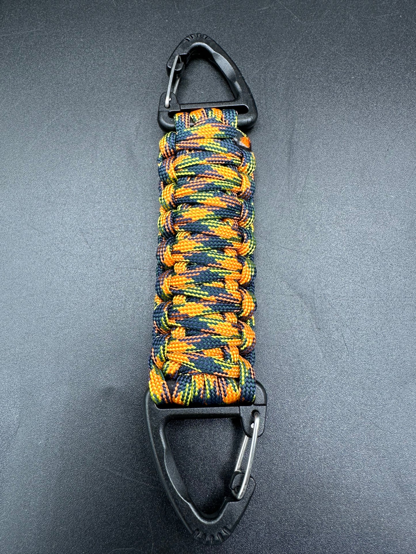 Our Tactical double ended triangle clip with a beautiful Paracord king cobra woven centre, are designed for your EDCs, molle, army bags and other field Attachments, handmade in this orange jungle camouflaged (orange black yellow) colours