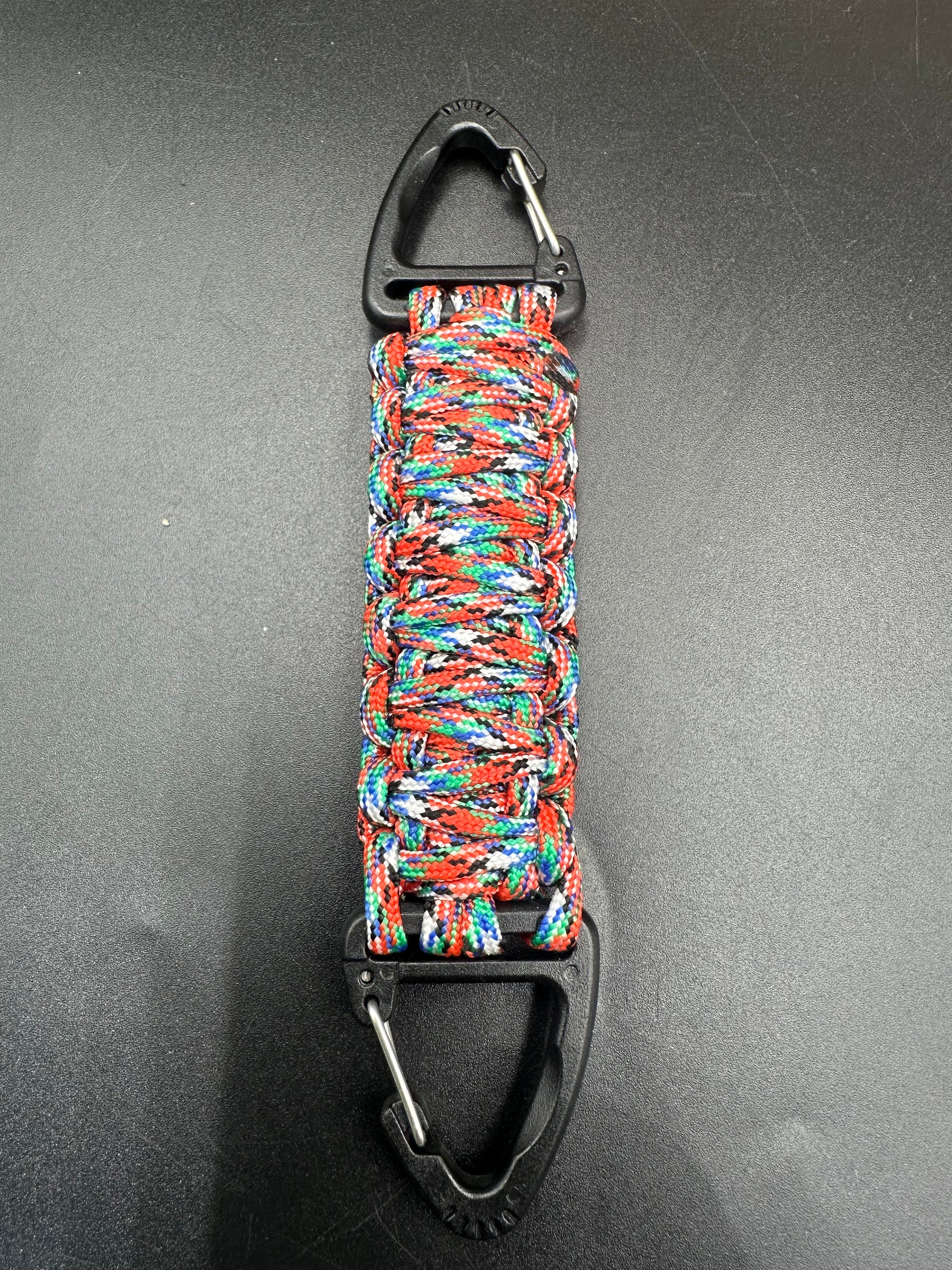 Our Tactical double ended triangle clip with a beautiful Paracord king cobra woven centre, are designed for your EDCs, molle, army bags and other field Attachments, handmade in this Urban Graffiti camouflage (red light blue greens whites) colour