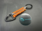 Tactical EDC Paracord keyring with a triangle clip and split ring, made in grey and neon Orange coloured shark jaw weave