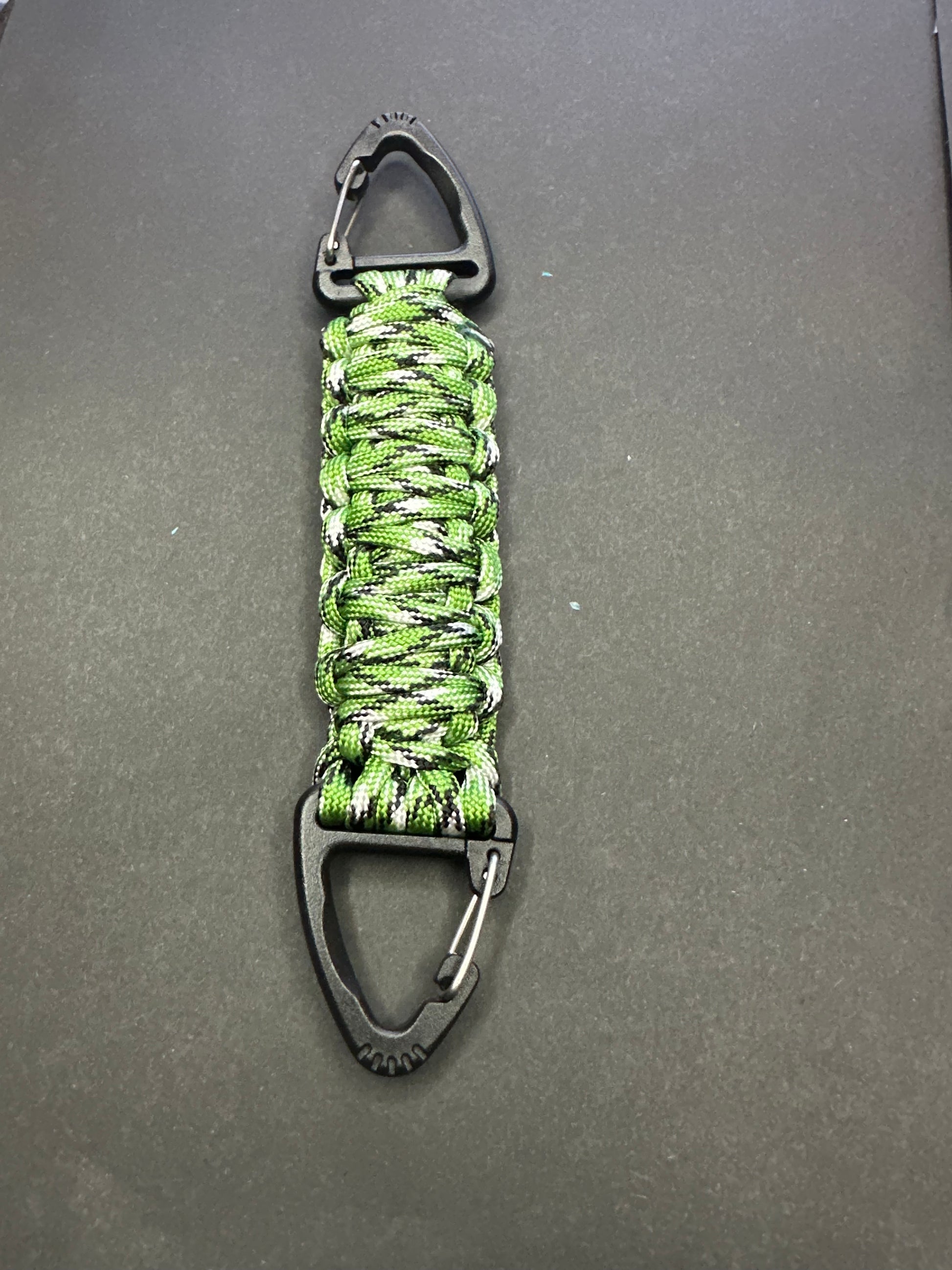 Our Tactical double ended triangle clip with a beautiful Paracord king cobra woven centre, are designed for your EDCs, molle, army bags and other field Attachments, handmade in this green grey camouflaged colour