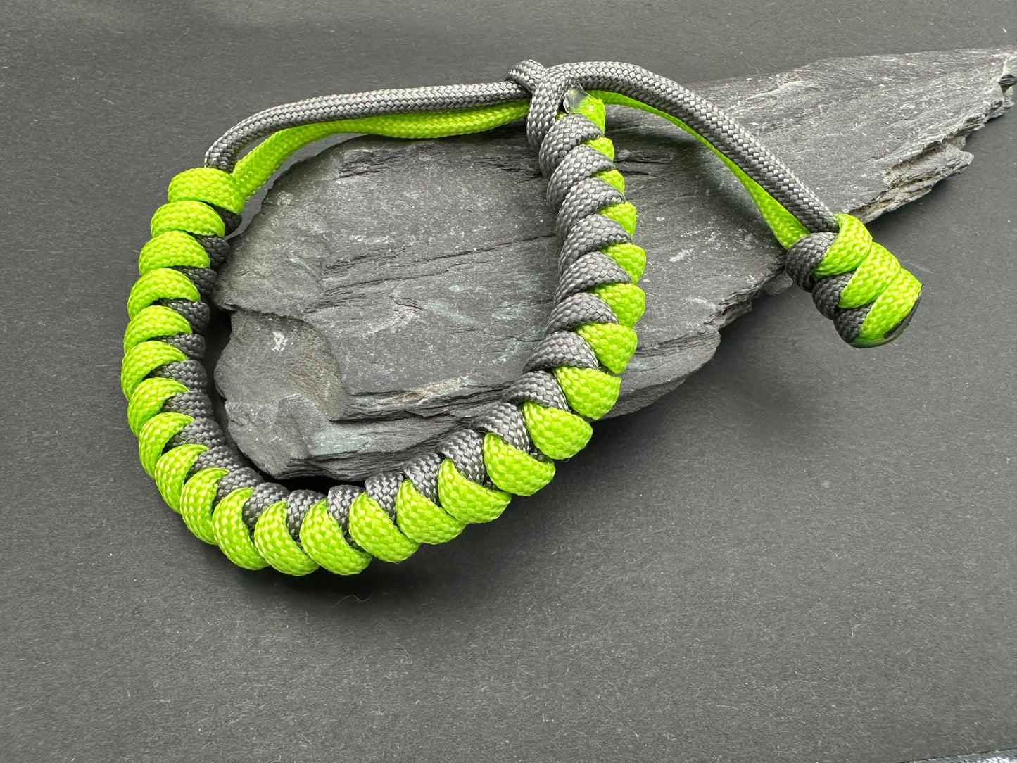 Paracord survival bracelets in Anthracite grey and neon green colour. the item is lightweight comfortable and handmade in a snake knott tactical design U.K.