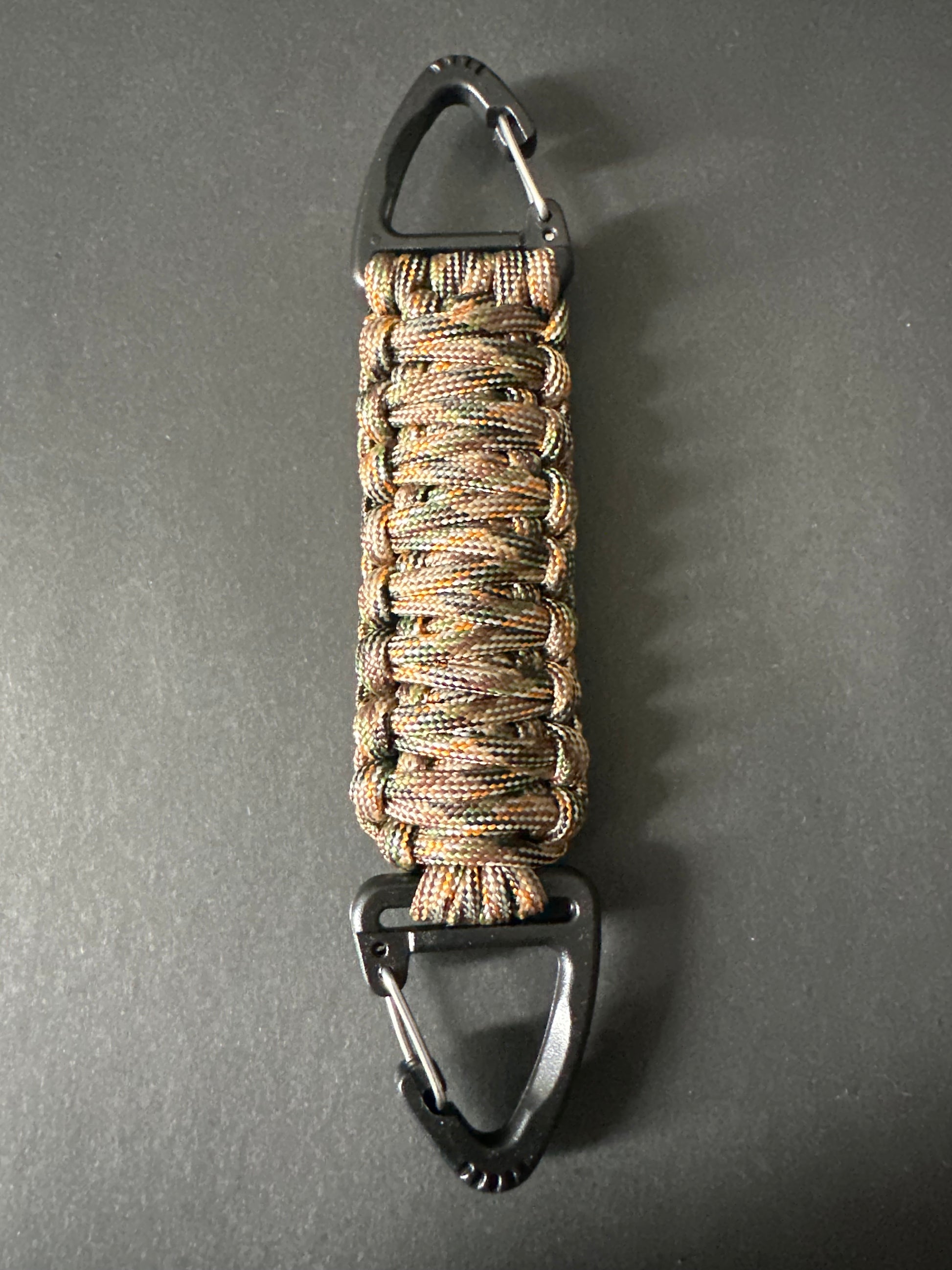 Our Tactical double ended triangle clip with a beautiful Paracord king cobra woven centre, are designed for your EDCs, molle, army bags and other field Attachments, handmade in this Autumn woodland camouflaged colour