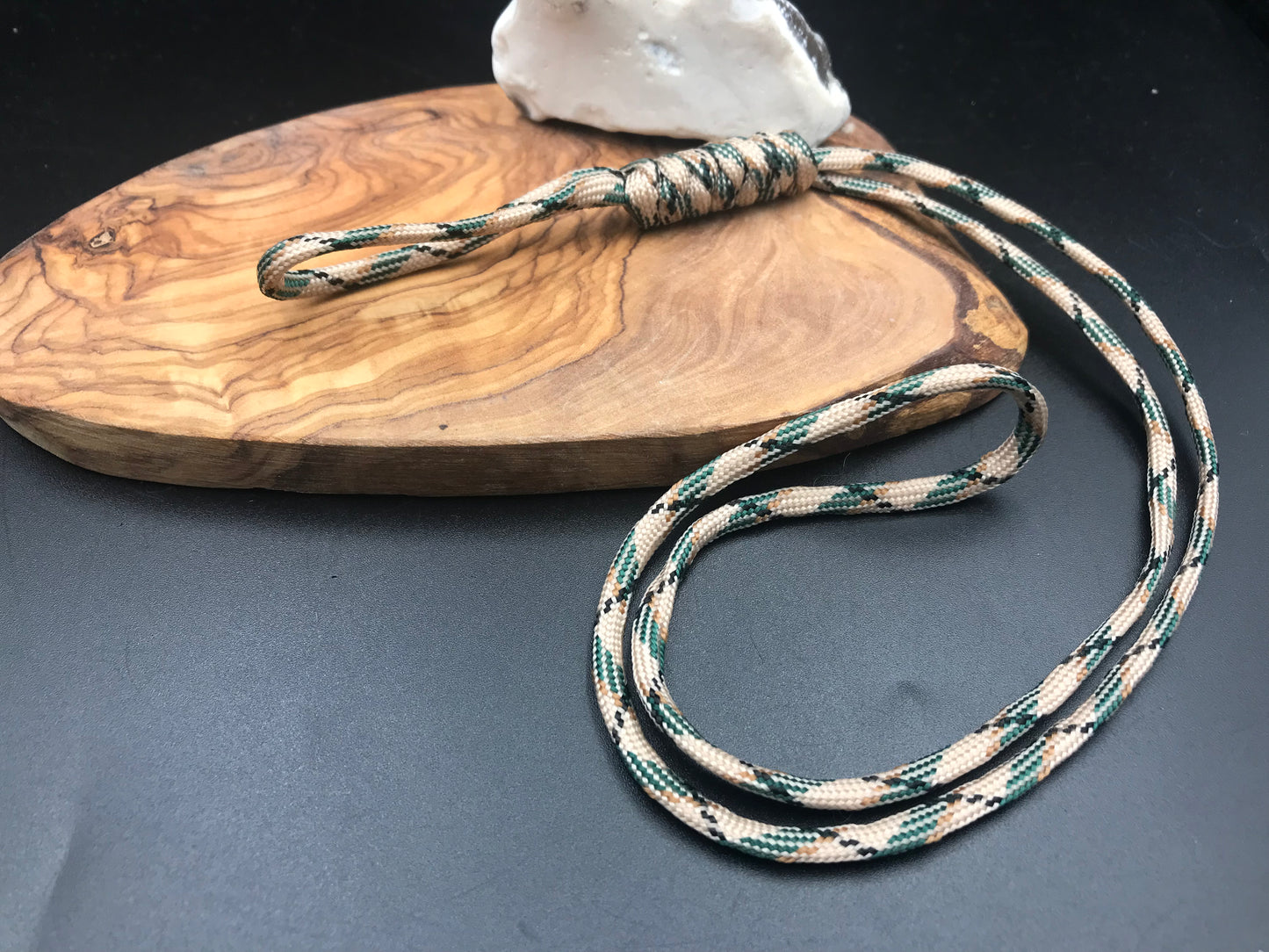 A desert camouflage paracord lanyard with a long loop design, displayed on a wooden surface.