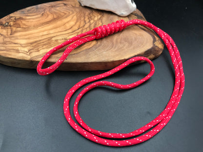 A red  paracord lanyard with a long loop design, displayed on a wooden surface.