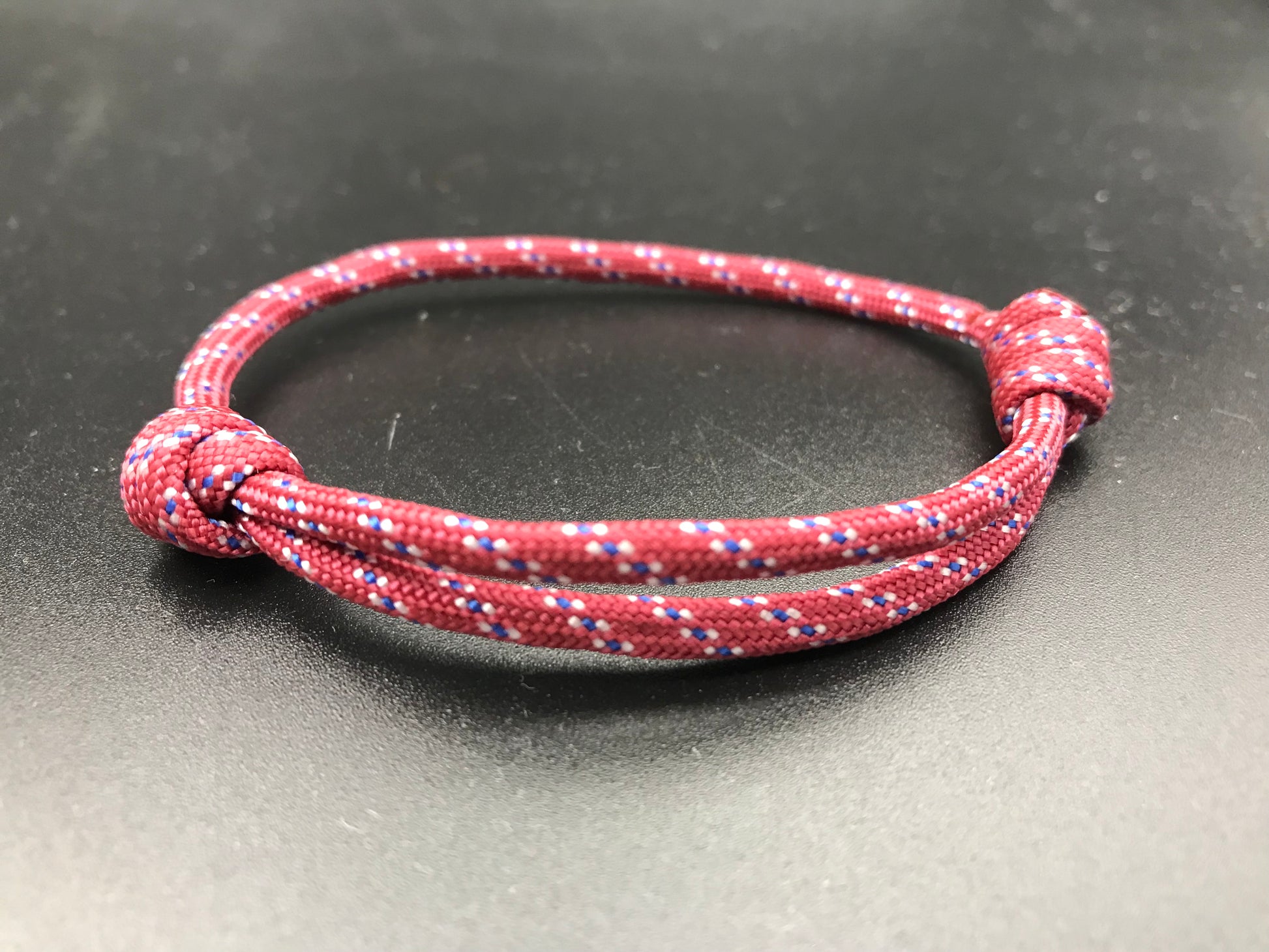 Paracord friendship bracelet in a dull red with white dots